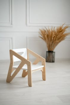 a wooden chair sitting on top of a white floor next to a potted plant