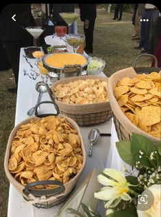 several baskets filled with chips sitting on top of a table next to flowers and wine glasses