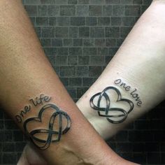 two people with tattoos on their arms holding hands and one has a heart shaped tattoo