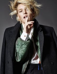 a woman with blonde hair wearing a green jacket and white shirt is posing for the camera