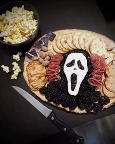 a platter with crackers, cheese and blackberries in the shape of a ghost