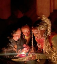 three girls looking at a lit candle in the dark