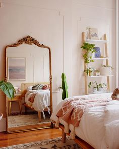 a bedroom with a bed, mirror and plants