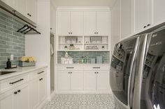 a kitchen with white cabinets and tile flooring next to a washer and dryer