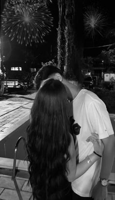 a man and woman kissing in front of fireworks