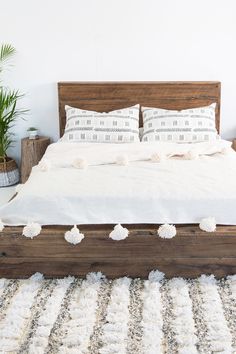 the bed is made with white linens and pom - poms on it