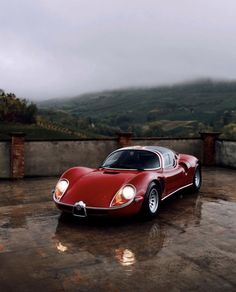 a red sports car parked on top of a wet parking lot