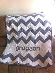 a gray and white chevroned blanket sitting on top of a couch next to a pillow