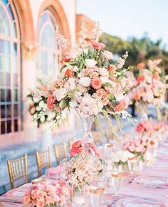 a long table is set with pink and white flowers in vases on top of it