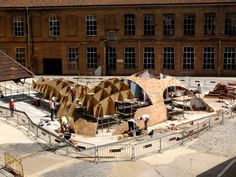 an aerial view of a building being constructed in front of a large brown brick building