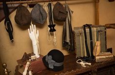 hats, gloves and other items are hanging on the wall next to an antique trunk