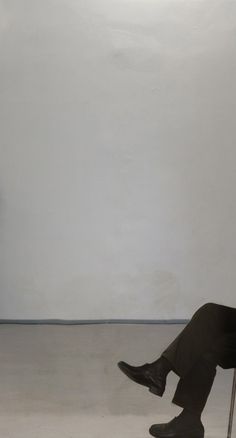 a man sitting on a chair in front of a white wall