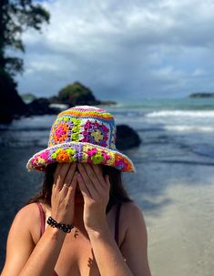 a woman covers her face while standing on the beach