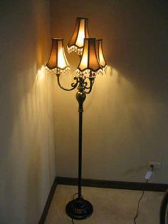 a floor lamp with three lamps on it in a corner next to a white wall