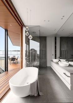 a large bathroom with two sinks and a bathtub in front of a window that looks out onto the water