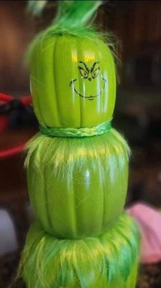 a stack of green pumpkins with faces painted on them