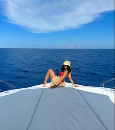 a woman sitting on the back of a boat in the middle of the ocean with her legs crossed