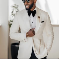 a man in a white tuxedo and black bow tie