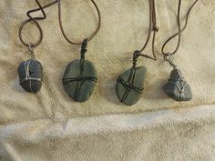 three stone pendants with wire wrapped around them sitting on a white cloth covered surface