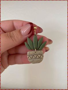 a person holding a small plant charm in their hand