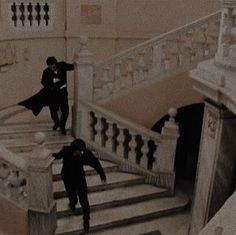 black and white photograph of two people walking down stairs in an old building with snow on the ground