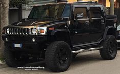 a black hummer truck parked on the side of the road in front of a building