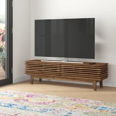 a flat screen tv sitting on top of a wooden entertainment center next to a sliding glass door