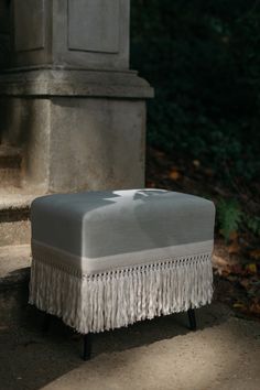 a white ottoman sitting on top of a cement step next to a grave with a cross