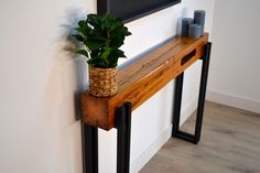 a potted plant sitting on top of a wooden shelf next to a framed picture