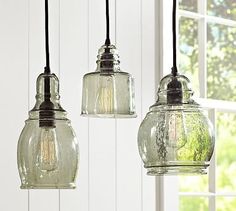 three clear glass pendant lights hanging from a ceiling