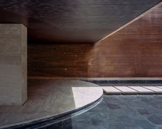 an empty swimming pool in the middle of a building with wooden walls and flooring