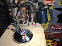 a counter top with an old fashioned coffee maker and various soda cans on the wall behind it