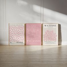 three books sitting on top of a hard wood floor next to each other in front of a white wall