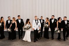 a group of people standing next to each other wearing tuxedos and gowns