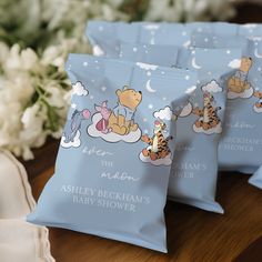 three baby shower bags with winnie the pooh characters on them and flowers in the background