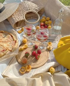 an assortment of food and drinks on a picnic blanket with strawberries, lemons, raspberries