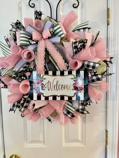 a welcome wreath with pink and black ribbons on the front door, decorated with an ornate welcome sign