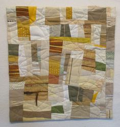 a piece of art that is made out of different colored squares and strips of fabric