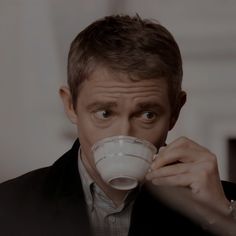 a man in a suit drinking from a cup