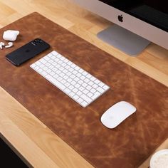 a desk with a keyboard, mouse and cell phone on it