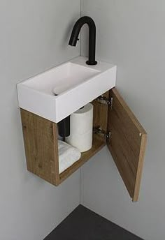 a bathroom sink with a wooden cabinet underneath it and a black faucet on the wall