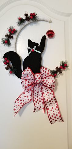 a door hanger with a black cat on it's side and red polka dot ribbon