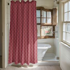 a red and white shower curtain hanging in front of a bathtub next to a window