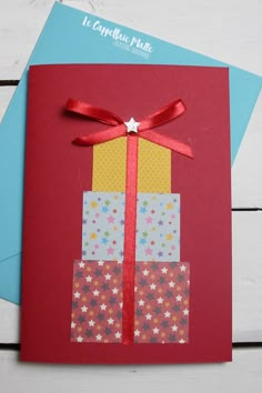 a red card with a gift box on it and a ribbon tied around the top