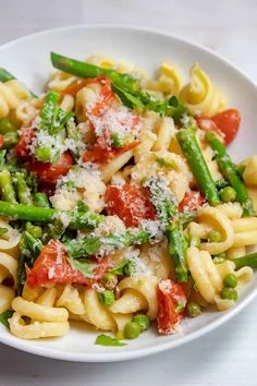 pasta with asparagus, tomatoes and parmesan cheese in a white bowl