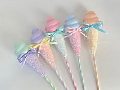 four candy cones with bows on them are lined up in a row and one has two lollipop sticks sticking out of it