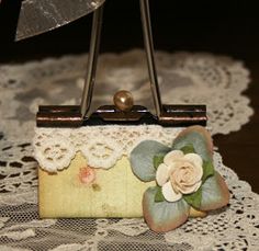 a close up of a small purse on a lace doily with a flower decoration