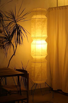 a lamp that is sitting next to a table and chair in a room with curtains