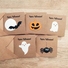 four brown envelopes decorated with halloween stickers on top of a wooden table next to each other