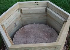 a wooden box sitting in the middle of some grass and rocks on top of it